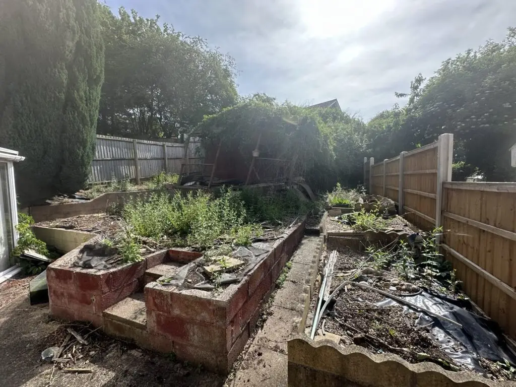 Overgrown back garden with crumbling raised beds before the Gedling refurbishment