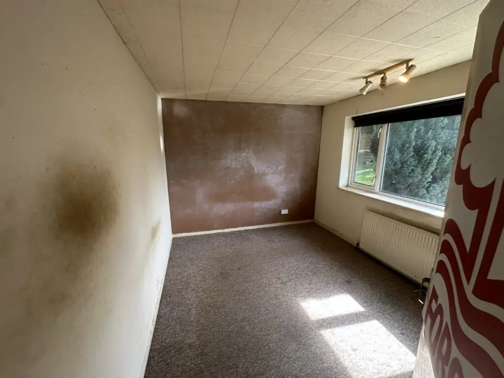 Bedroom with damp staining on the wall before the refurbishment