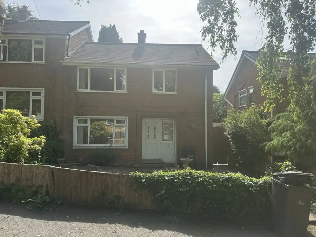 Front of the Gedling property before refurbishment, with overgrown hedge and old fence