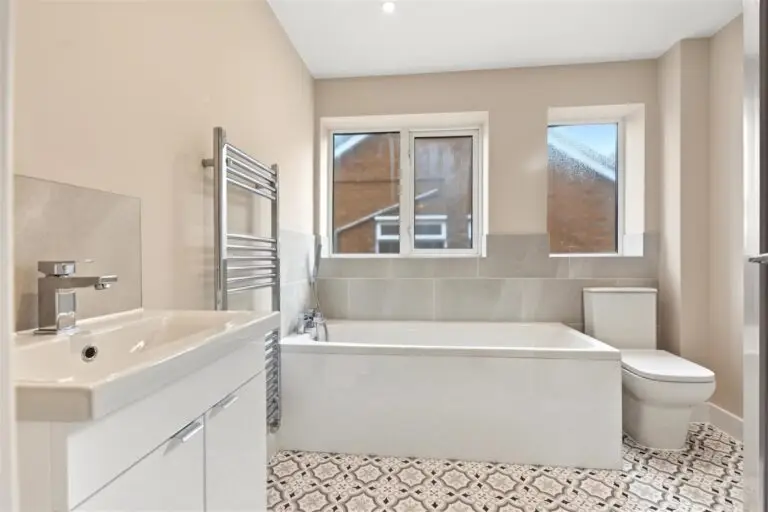 New bathroom with bath, vanity unit, heated towel rail and patterned floor tiles